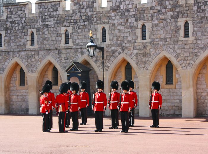 British guards in red uniforms standing in formation outside a historic stone building, illustrating big no no customs.