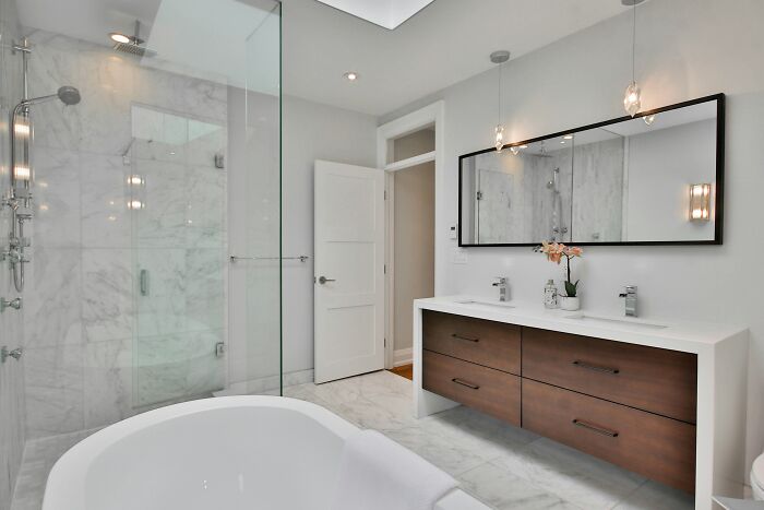 Modern bathroom with glass shower and double vanity, ideal uncommon hacks for women living alone for comfort and safety.