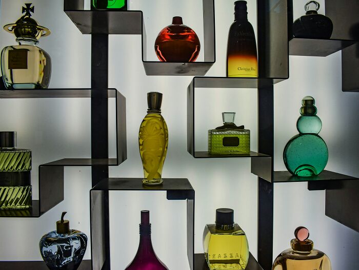 Variety of colorful perfume bottles displayed on modern shelves, illustrating unique hobbies that give netizens the ick.