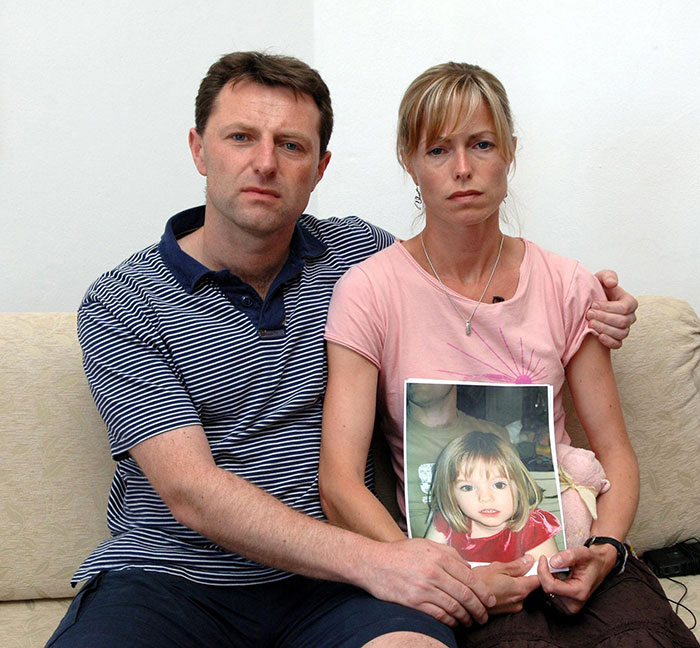 Couple sitting on a couch holding a photo of young girl, related to disturbing new theory in Madeleine McCann disappearance.