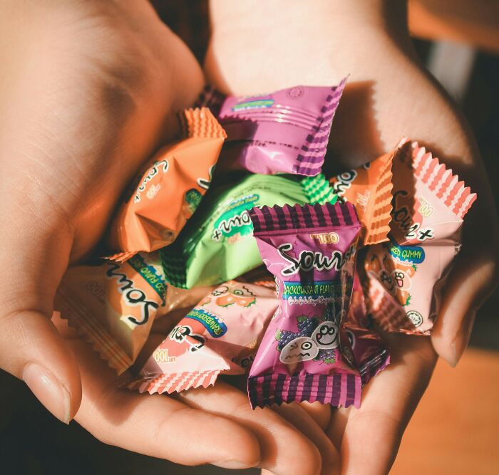 Hands holding colorful wrapped candies, symbolizing a priceless reward after spending just a dollar.
