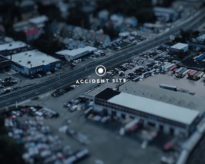 Aerial view of an accident site on a busy road near industrial buildings and parked vehicles. Aerial view of an accident site on a busy road near industrial buildings and parked vehicles.