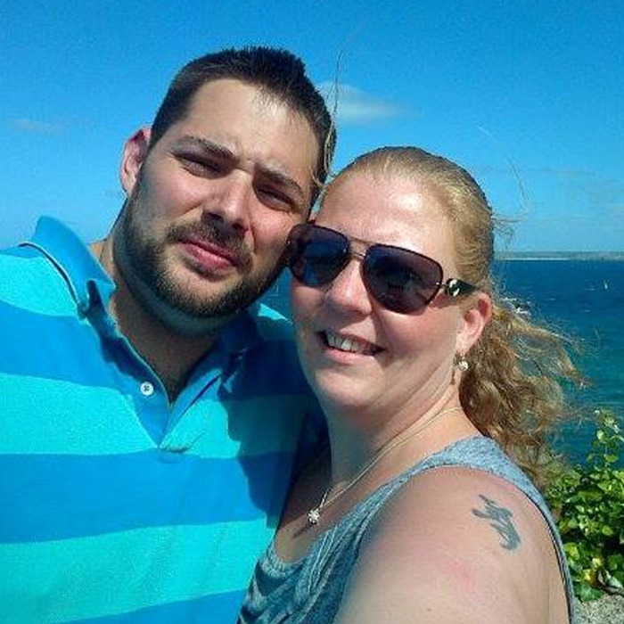 Man abandoned as baby in plastic bag and left in toilet reunited with birth family, smiling outdoors near the ocean.