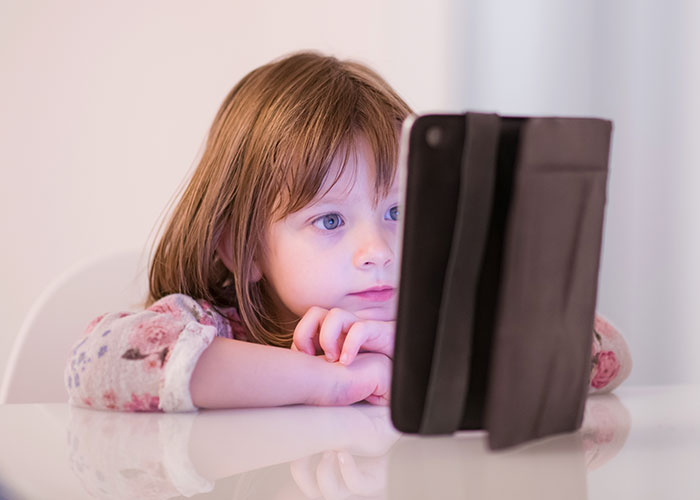 Young girl intently watching a tablet, illustrating challenges of man not prepared to deal with SIL&rsquo;s kid staying over.