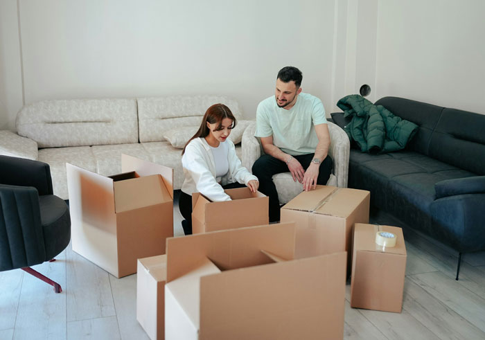 Couple surrounded by moving boxes, discussing living arrangements and sharing 50/50 financial split in modern living room. Couple surrounded by moving boxes, discussing living arrangements and sharing 50/50 financial split in modern living room.
