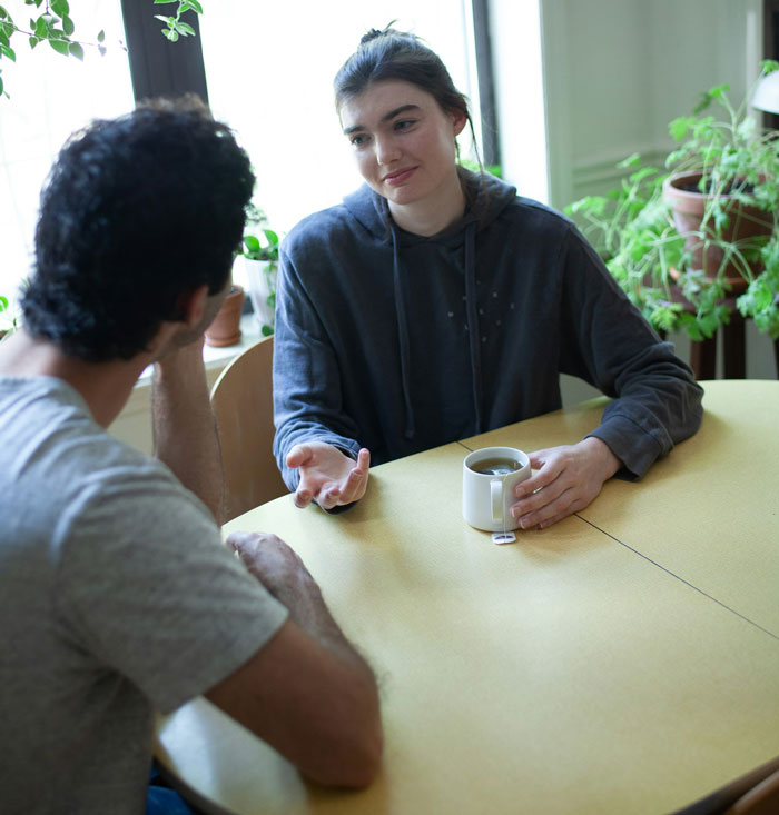 Couple having serious conversation at the table, woman looks upset while discussing moving in and splitting 50/50 expenses. Couple having serious conversation at the table, woman looks upset while discussing moving in and splitting 50/50 expenses.