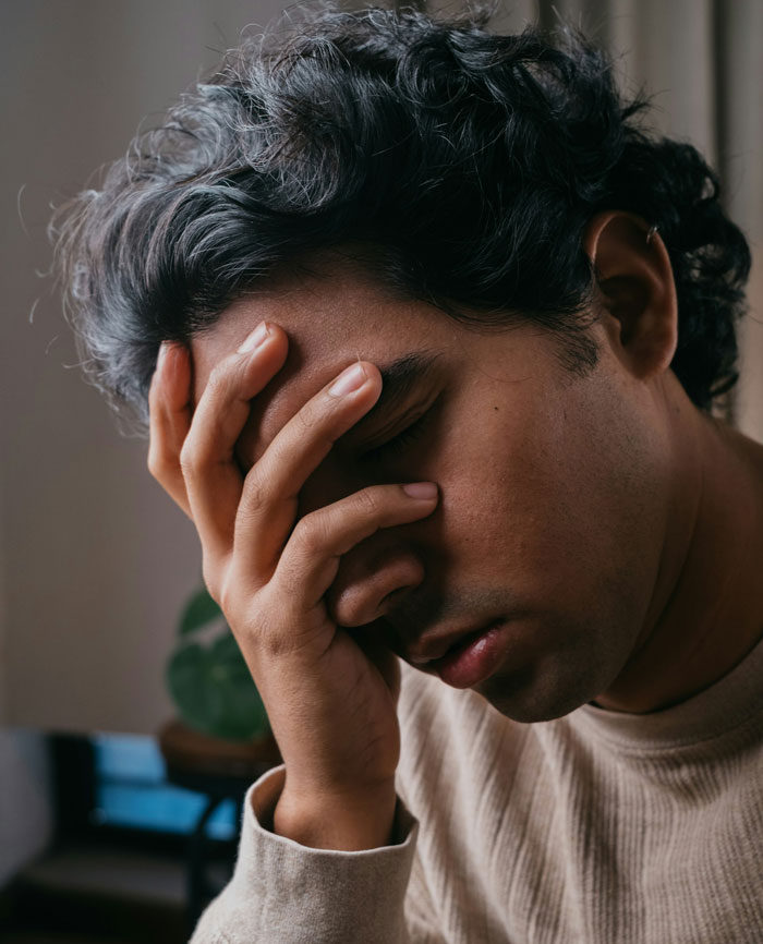 Young man looking stressed and frustrated, covering his face with his hand in a moment of relationship conflict. Young man looking stressed and frustrated, covering his face with his hand in a moment of relationship conflict.
