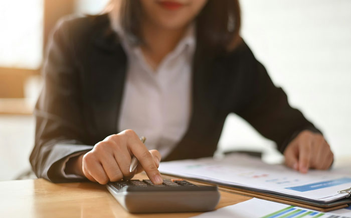 Woman furious using calculator, reviewing finances and documents, illustrating boyfriend refusing move-in without splitting 50/50 costs. Woman furious using calculator, reviewing finances and documents, illustrating boyfriend refusing move-in without splitting 50/50 costs.