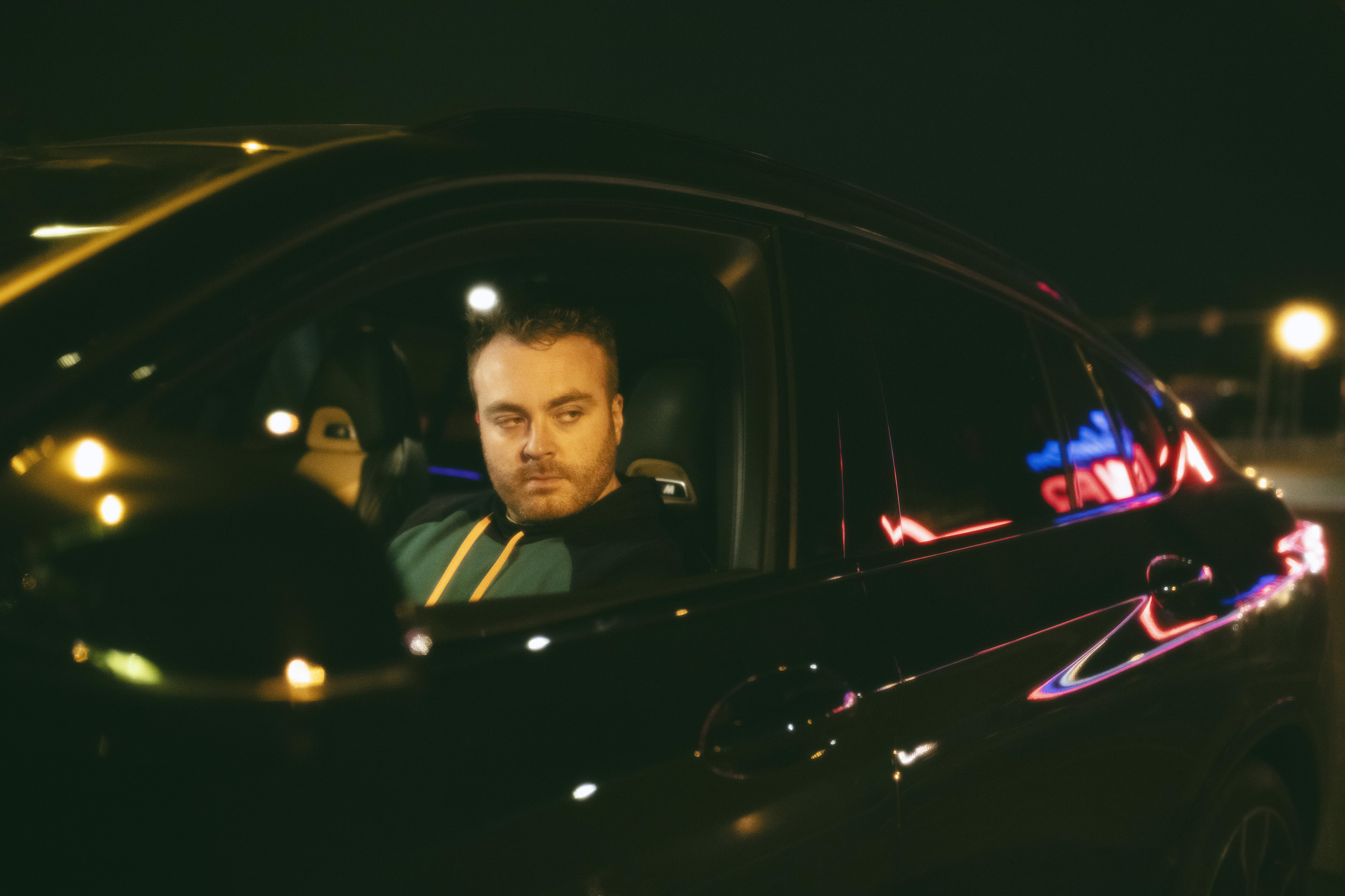 Man inside a car at night checking side mirror while practicing safe driving facts for those with a driving license