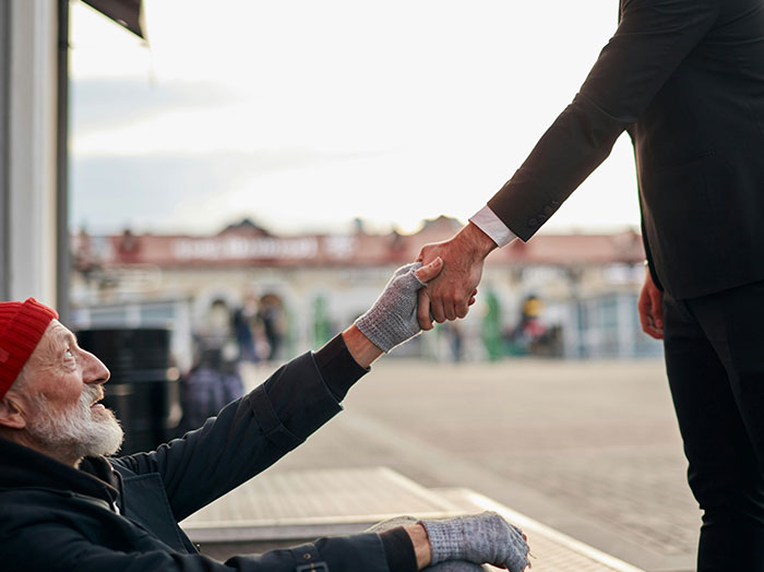 Man in suit helping homeless man up, illustrating moments when men made women think wow he stands out.