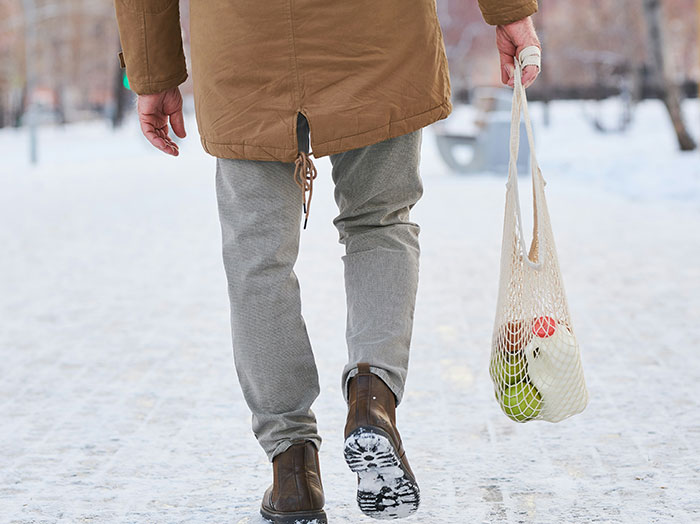Man walking on snowy path carrying a tote bag, illustrating moments when men made women think he stands out