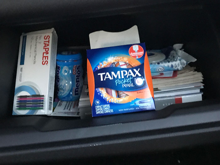 Car glove compartment with tampons, staples, gum, and tissues illustrating men making women think wow he stands out moments.
