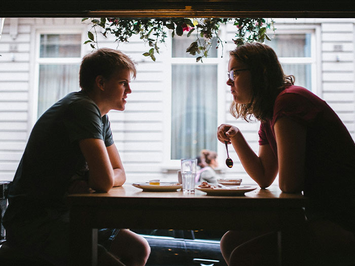 Two people having an engaging conversation at a table, capturing moments where men stand out in romantic settings.