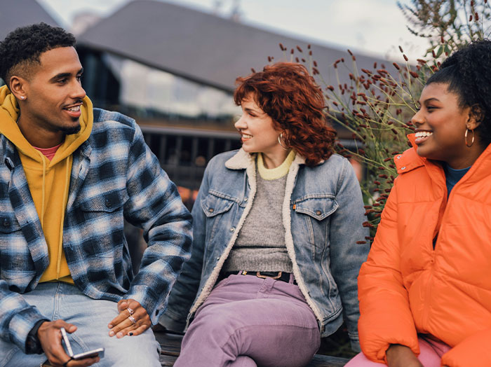 Three friends chatting outdoors, capturing moments when men made women think wow he stands out in rom-com style.