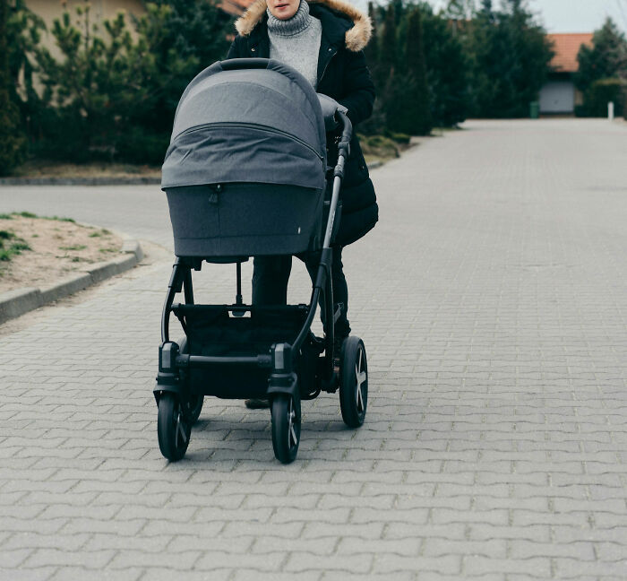 Person pushing a stroller on a paved path, illustrating themes of parenting and worst parents stories.