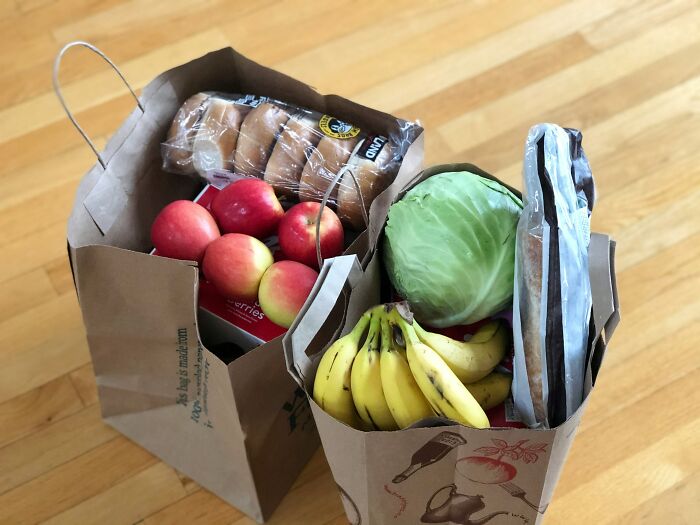Two grocery bags filled with fresh fruits, vegetables, and bread showcasing everyday habits related to poor people.