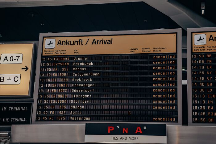 Airport arrival board displaying multiple cancelled flights, illustrating expert tips on the cheapest airfare timing to buy plane tickets.