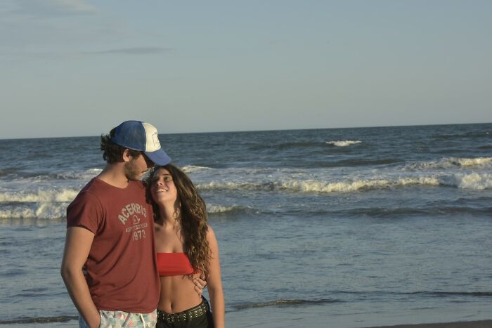 Young couple embracing on the beach with waves in the background, reflecting on no peaceful solution to current situation.