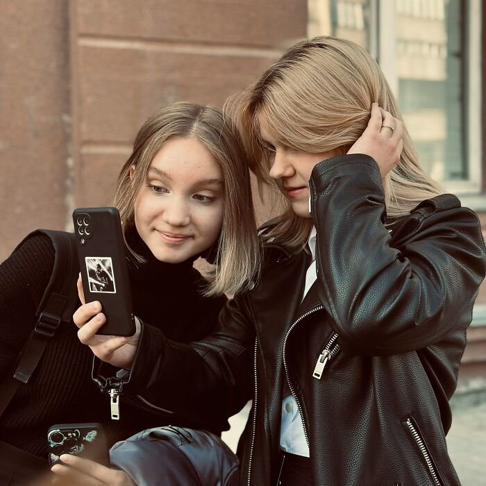 Two young women taking a selfie together outdoors, capturing moments of friendship and trust.