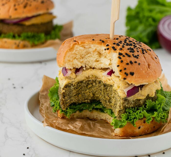 Close-up of a healthy veggie burger with lettuce and onions on a sesame seed bun, showcasing best processed foods for weight loss.
