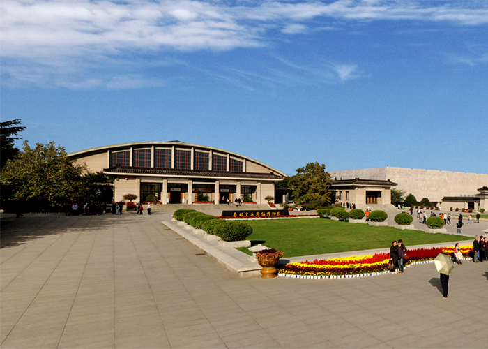 Tourists visiting an ancient historic site with 2000-year-old statues near a large open plaza and garden area. Tourists visiting an ancient historic site with 2000-year-old statues near a large open plaza and garden area.