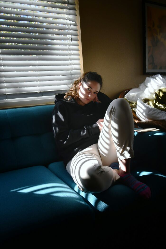 Young woman sitting alone on a couch in sunlight, reflecting on moments that drove away potential life partners.