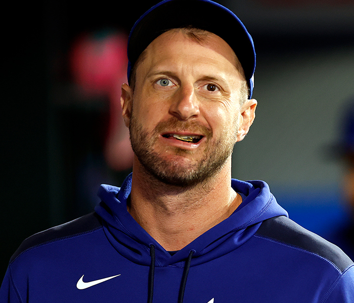 Male celebrity with noticeable body anomaly wearing a blue hoodie and cap, captured candidly during an event.