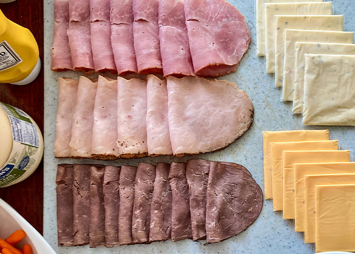 Assortment of deli meats and cheese slices displayed on a cutting board as healthy foods to skip eating.