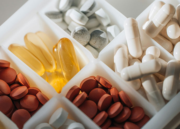 Various pills and capsules organized in a white pill organizer, representing healthy foods to skip eating advice.