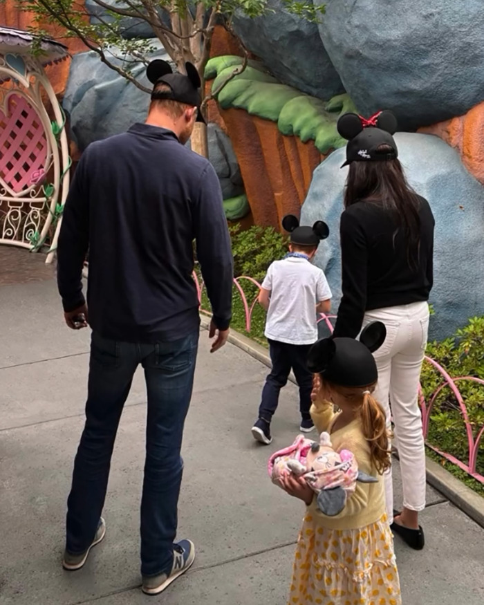 Family wearing mouse ear hats at a theme park, highlighting Meghan Markle accused of treating her kids like accessories.