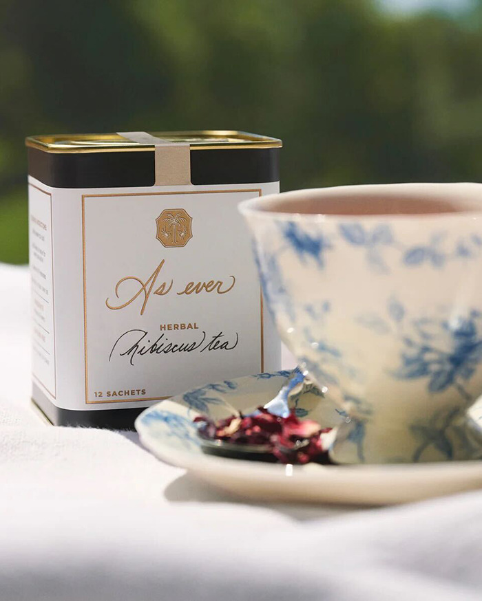 As ever herbal hibiscus tea box with a blue floral tea cup and saucer on a white cloth background. As ever herbal hibiscus tea box with a blue floral tea cup and saucer on a white cloth background.
