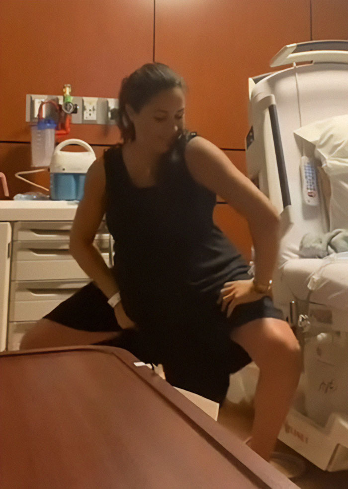 Pregnant woman in a black dress twerking in a hospital room, sparking Meghan Markle pregnancy conspiracy theories.