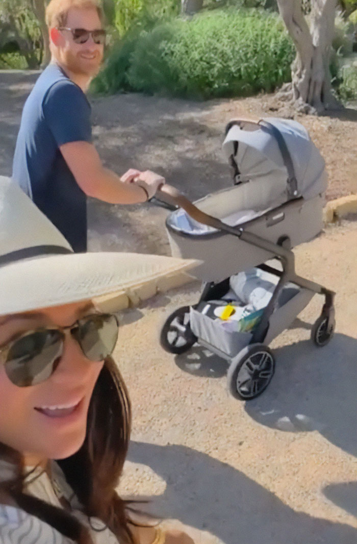 Meghan Markle with Prince Harry outdoors pushing a stroller, sparking twerking pregnancy conspiracy theory discussion.