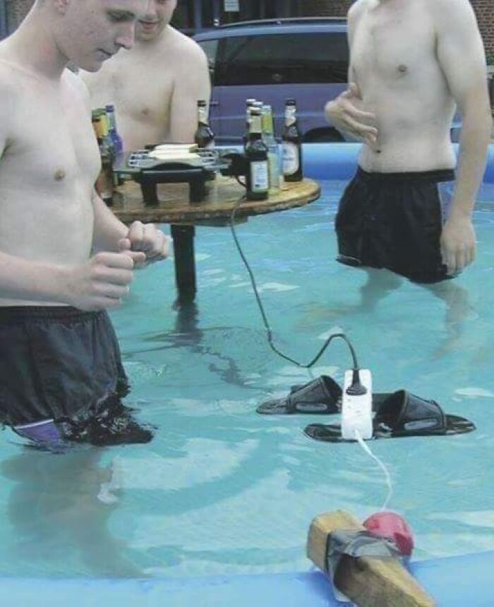 Three men standing in a pool with a risky power strip setup near water, illustrating men doing dumb things.