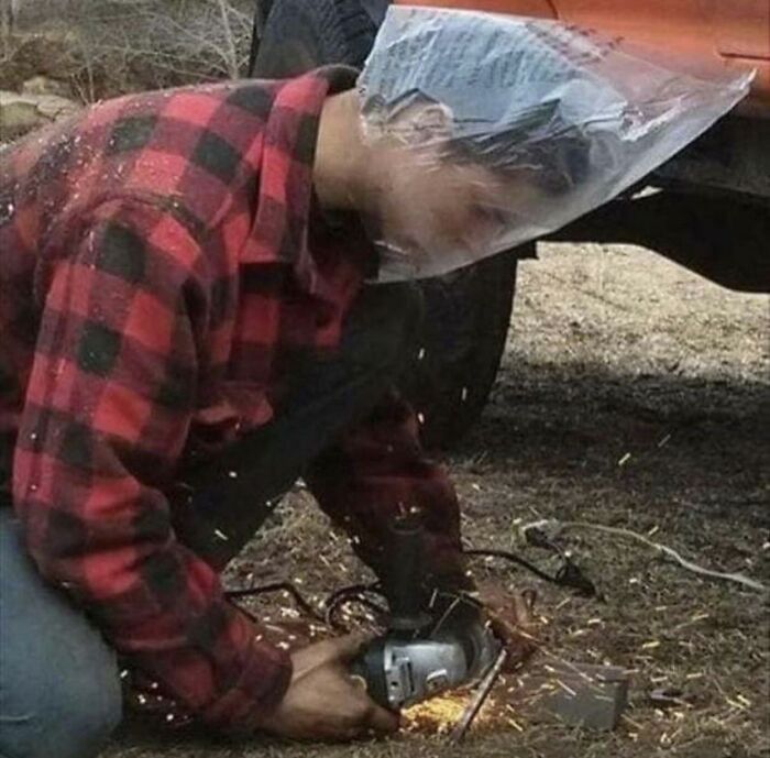 Man doing dumb things uses plastic bag over head while cutting metal with angle grinder outdoors sparks flying