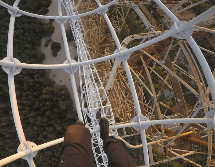 Man climbing a tall rusted metal structure without safety gear showing reckless behavior explaining why men live shorter.