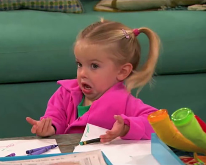 Young beloved child star from Good Luck Charlie making a surprised face while sitting at a table with crayons.