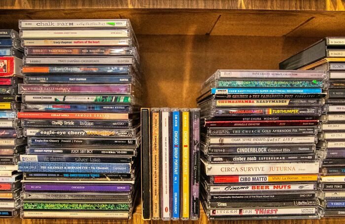 Stacks of assorted CDs and cases on wooden shelves, highlighting sneaky details found by readers of terms and conditions.