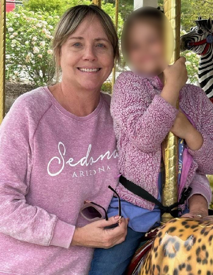 Woman smiling and sitting next to child on carousel, linked to teacher resigns over controversial t-shirt during White House trip