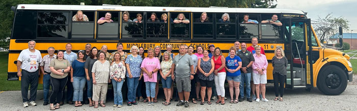 Group of teachers posing in front of a school bus during a White House class trip amid controversial t-shirt issue.