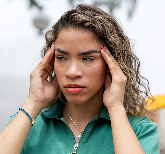 Woman with curly hair looking stressed and worried, holding her temples, relating to child protective services conflict. Woman with curly hair looking stressed and worried, holding her temples, relating to child protective services conflict.