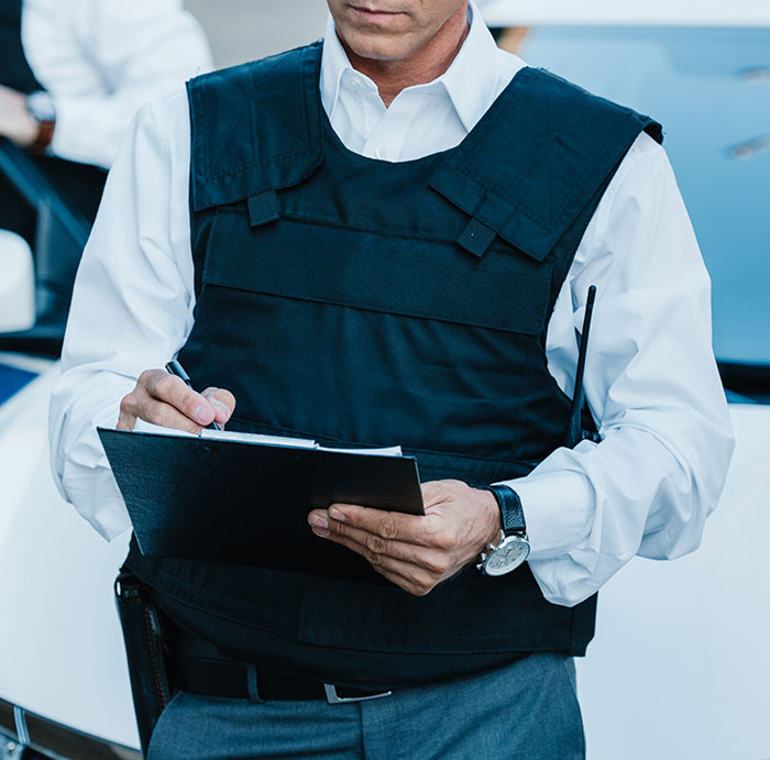 Child Protective Services agent wearing a bulletproof vest writing notes on a clipboard during an investigation. Child Protective Services agent wearing a bulletproof vest writing notes on a clipboard during an investigation.