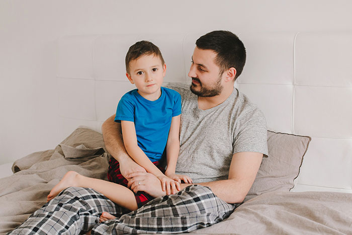 Man holding young boy on bed, symbolizing absent grandma trying to reconnect after many years and facing rejection. Man holding young boy on bed, symbolizing absent grandma trying to reconnect after many years and facing rejection.