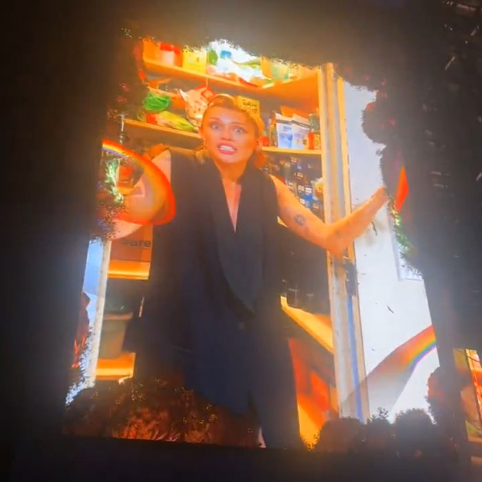 Person standing in a brightly lit pantry, reacting with wide eyes and open arms amid a colorful Pride-themed backdrop. Person standing in a brightly lit pantry, reacting with wide eyes and open arms amid a colorful Pride-themed backdrop.