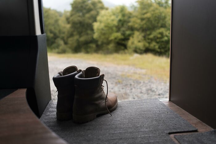 Brown boots placed by the open door inside a home with a view of the outdoors, illustrating uncommon hacks for women living alone.