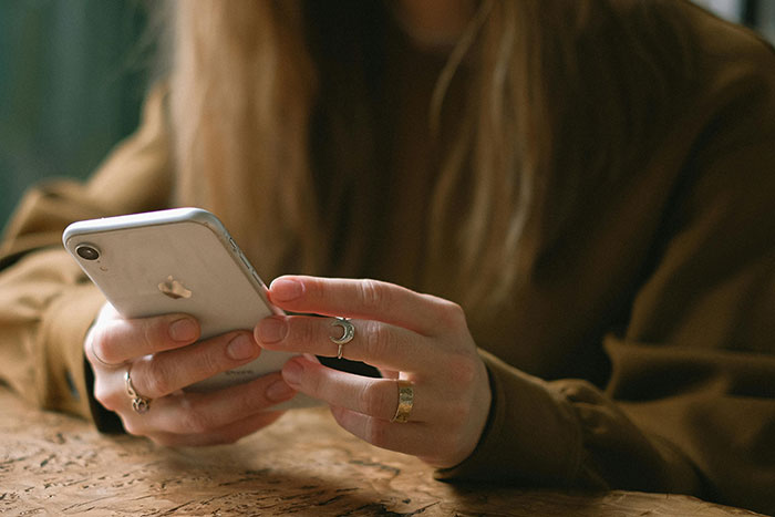 Woman holding a smartphone, seeking advice on how to deal with her mom threatening to call CPS, wearing rings. Woman holding a smartphone, seeking advice on how to deal with her mom threatening to call CPS, wearing rings.