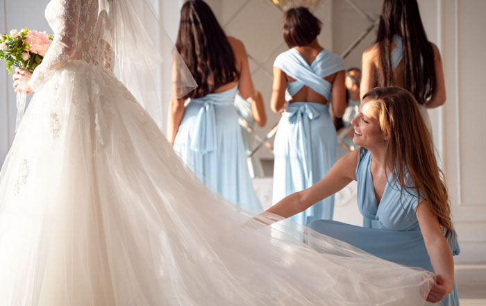 Bride in white wedding dress with bridesmaids in blue dresses, highlighting bride asking mom not to wear white at wedding. Bride in white wedding dress with bridesmaids in blue dresses, highlighting bride asking mom not to wear white at wedding.