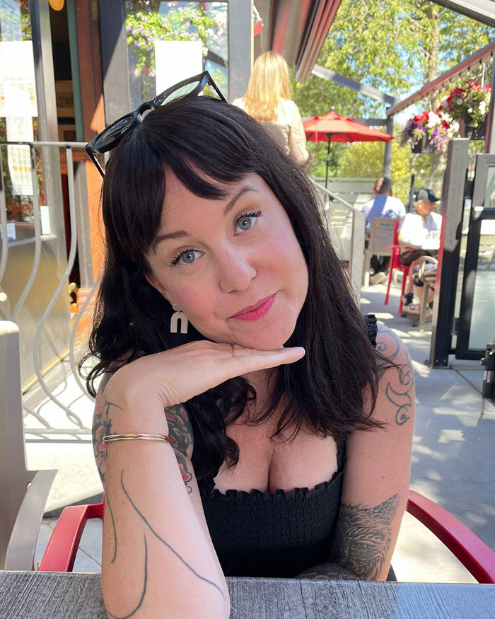 Single mom with early-onset Alzheimer's sitting outdoors at a cafe, resting her chin on her hand and looking thoughtfully.