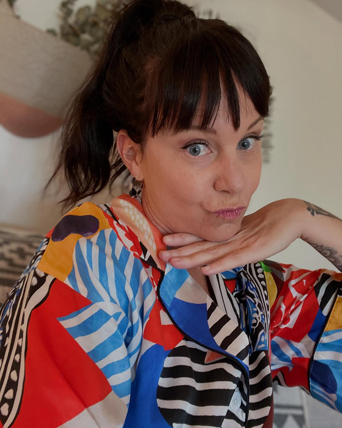 Single mom with early-onset Alzheimer's posing indoors, wearing a colorful patterned shirt with thoughtful expression.