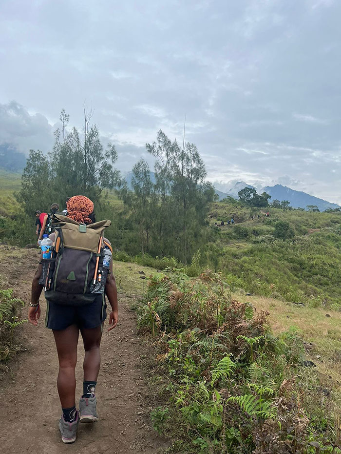 Hiker with backpack walking on a trail surrounded by greenery and mountains in the background on volcano tours. Hiker with backpack walking on a trail surrounded by greenery and mountains in the background on volcano tours.